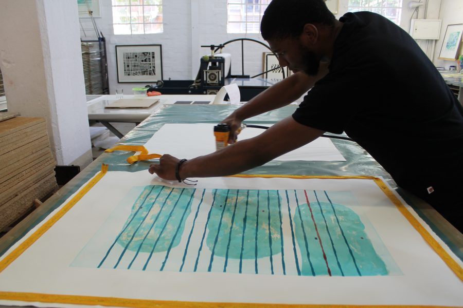 Step 3: Sbongiseni staples the print down. Once dried and flattened, the work will be cropped and framed. 