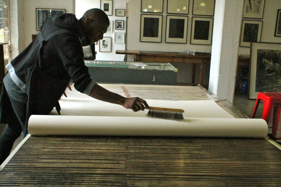 First, Sbongiseni brushes the paper to make sure it is completely clean for printing.