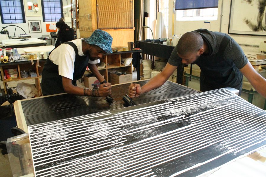 Neo and Sbongiseni apply the first layer of ink to the woodcut. 