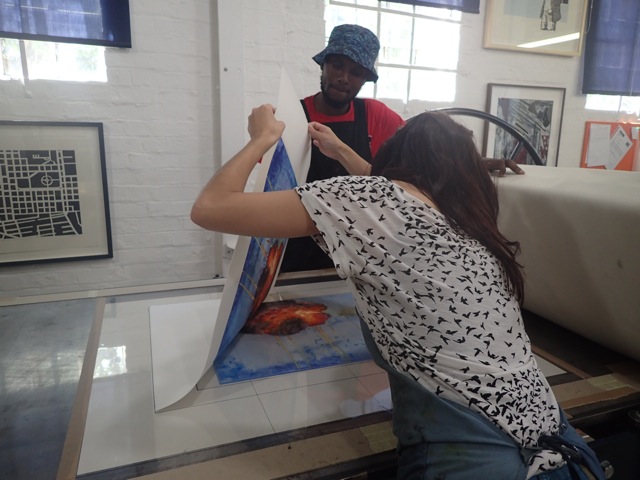 DKP printers Kim-Lee Loggenberg and Neo Mahlasela lift the paper from the Perspex plate after running it through the press.